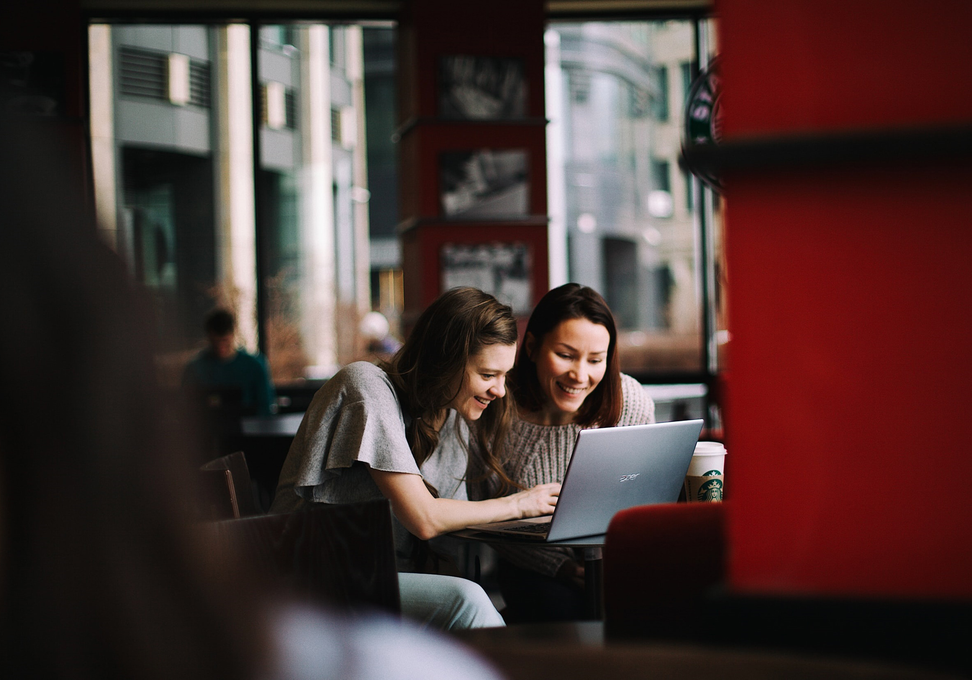 Mujeres riendo y trabajando juntas con un portátil